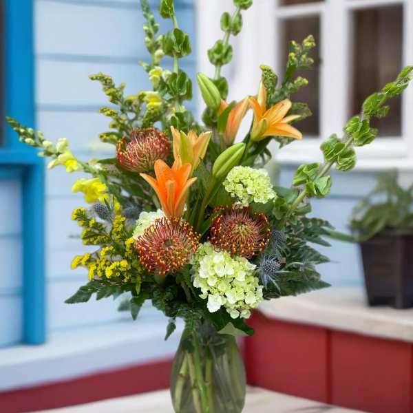Mixed bouquet with orange lilies and green hydrangeas in a glass vase