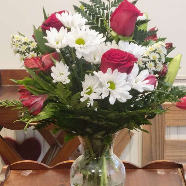 Bouquet of red roses and white daisies in a clear glass vase