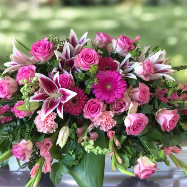 Pink roses and lilies arranged in a low vase centerpiece