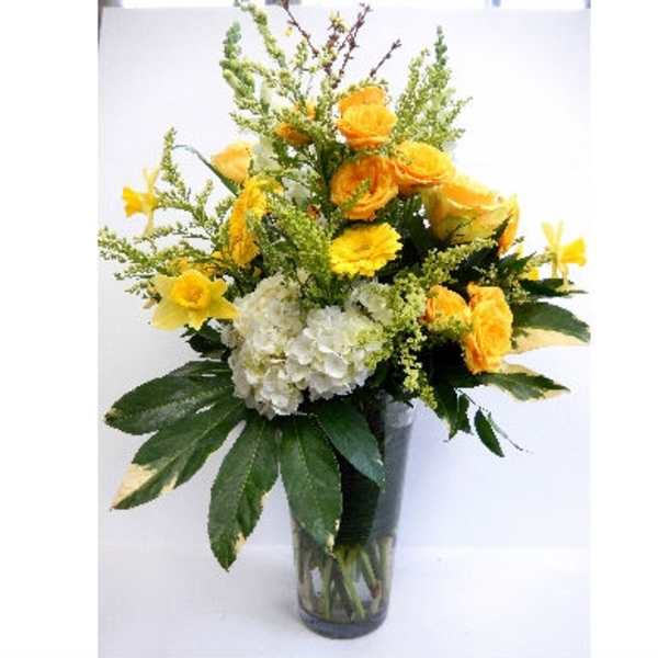 Yellow flowers and white hydrangea in a clear glass vase