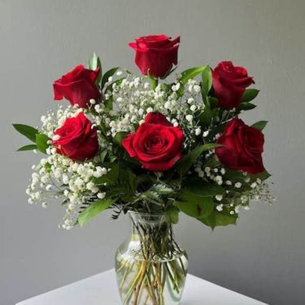 Red roses arranged in a clear glass vase with white baby's breath