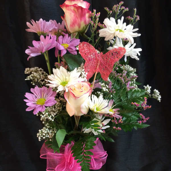 Pink and white mixed bouquet in a glass vase with a pink ribbon