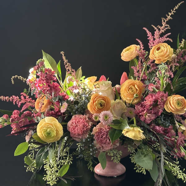 Large mixed floral arrangement in a pink pedestal vase