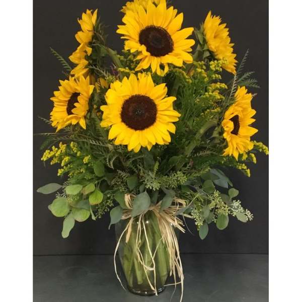 Sunflower arrangement in a glass vase with raffia tie