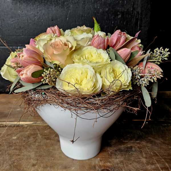 Low floral arrangement of cream roses and pink tulips in a white vase