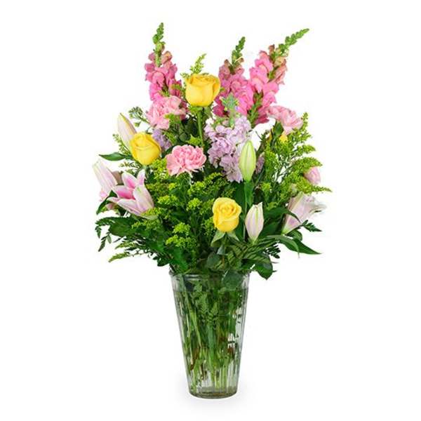 Mixed bouquet of pink and yellow flowers in a clear glass vase