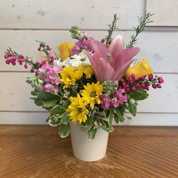 Mixed bouquet in a white vase with pink lilies, yellow daisies, and roses