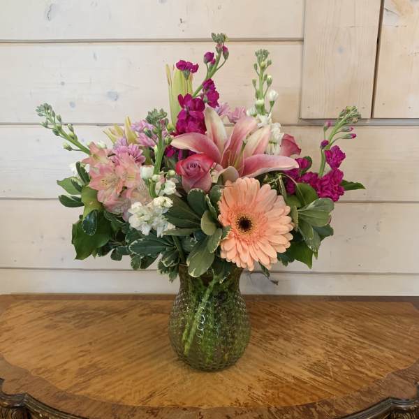 Mixed pink and peach flowers arranged in a glass vase