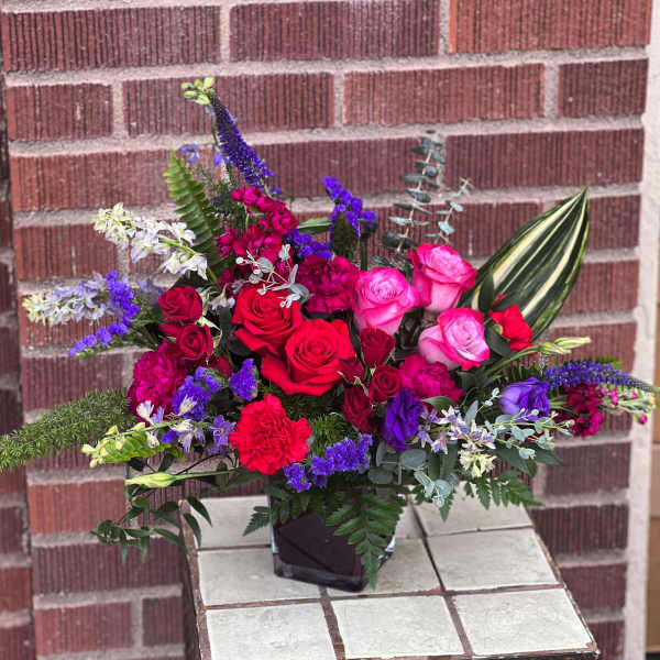 Bright mixed bouquet of red, pink, and purple flowers in a black vase