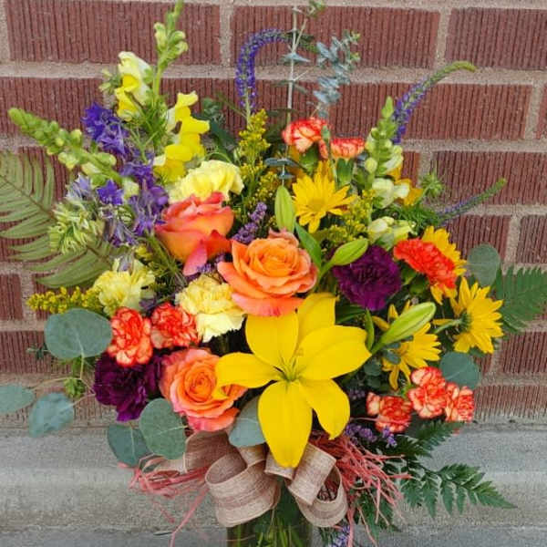 Colorful mixed bouquet in a glass vase with roses and lilies