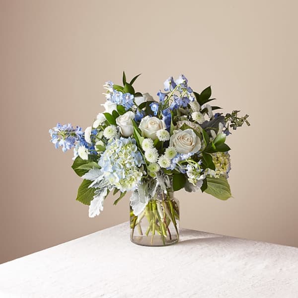 Blue and white floral arrangement in a clear glass vase
