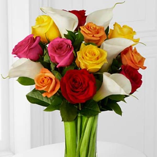 Bouquet of multicolored roses and white calla lilies in a glass vase