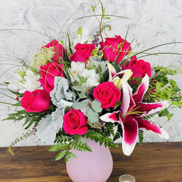 Pink roses and white lilies arranged in a pink vase