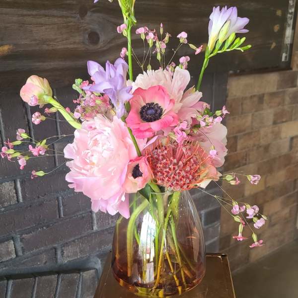 Pink and lavender flowers arranged in an amber glass vase