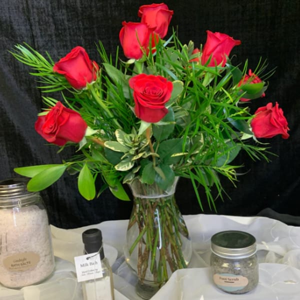 Red roses arranged in a clear glass vase with greenery