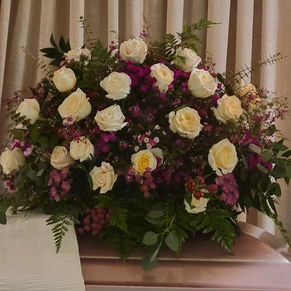 White roses and purple flowers arranged in a large funeral spray