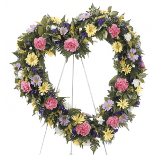 Heart-shaped floral wreath on a stand with pink, yellow, purple, and white flowers