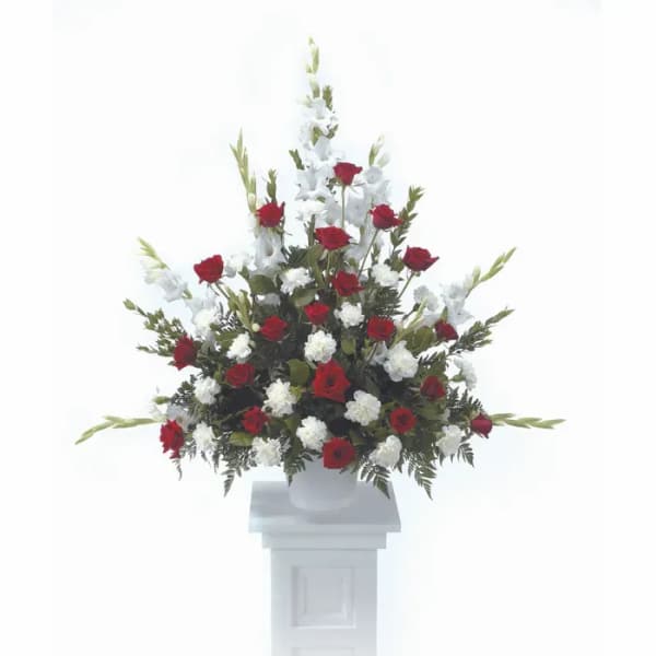 Red and white floral spray in a white urn on a pedestal