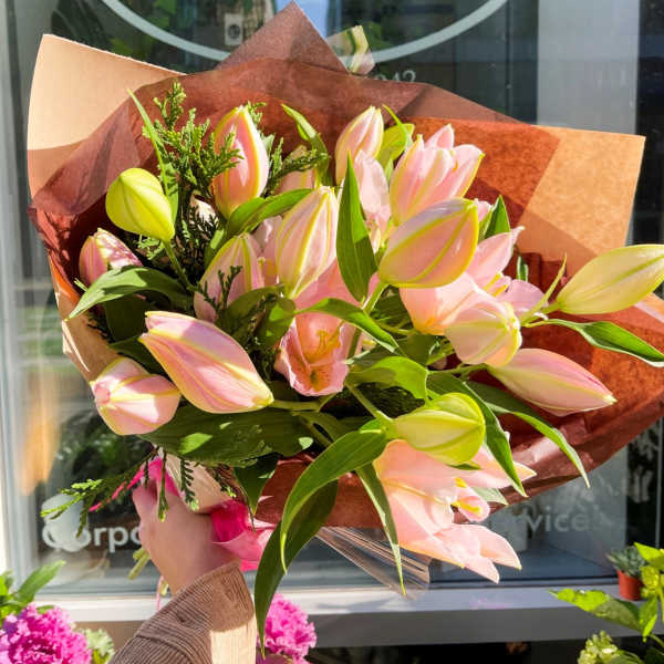 Bouquet of pink and yellow tulips wrapped in brown paper