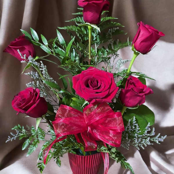 Bouquet of red roses in a ribbed vase with a red bow