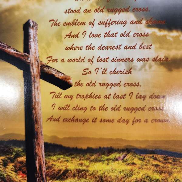 A printed memorial poem with a wooden cross against a cloudy sky