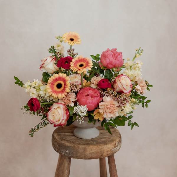 Mixed pink and cream bouquet in a white pedestal vase