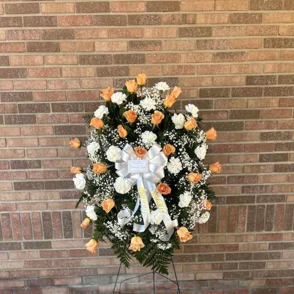 Standing funeral wreath of orange roses and white carnations on an easel