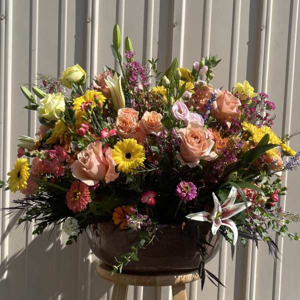 Large mixed bouquet in a dark bowl vase with pink, yellow, and white blooms