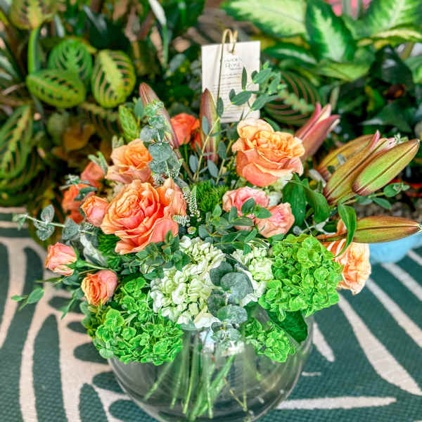 Peach roses and green hydrangeas in a clear glass vase