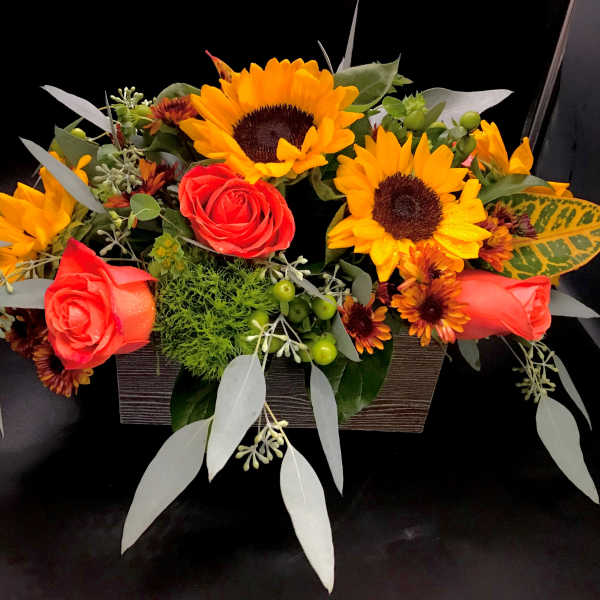 Arrangement of red roses and yellow sunflowers in a rectangular container