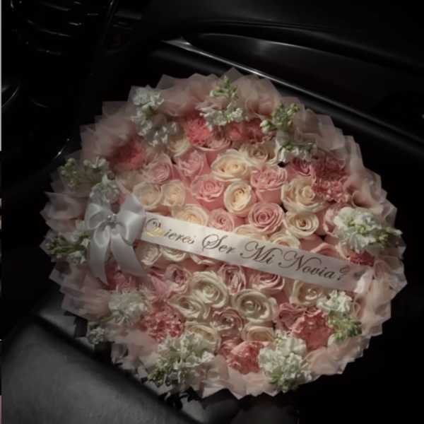 Round bouquet of pink and cream roses with a ribbon banner
