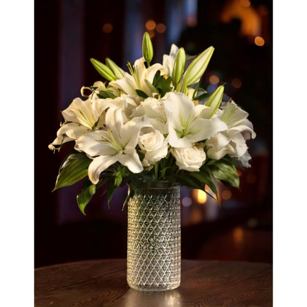 White lilies and roses arranged in a textured glass vase
