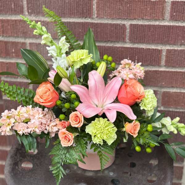 Pink lily and peach rose arrangement in a pink vase
