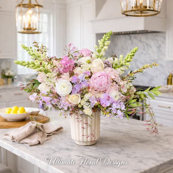 Large pastel floral arrangement in a white vase on a kitchen island