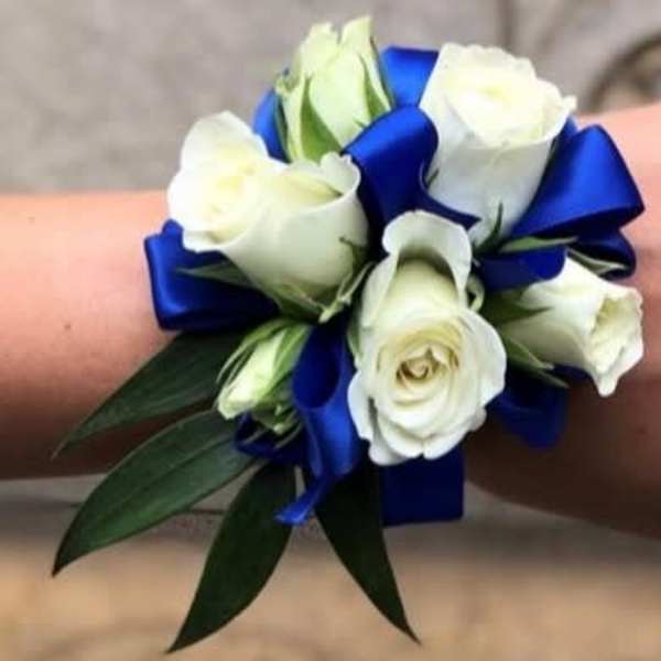 White rose wrist corsage with blue ribbon and green leaves