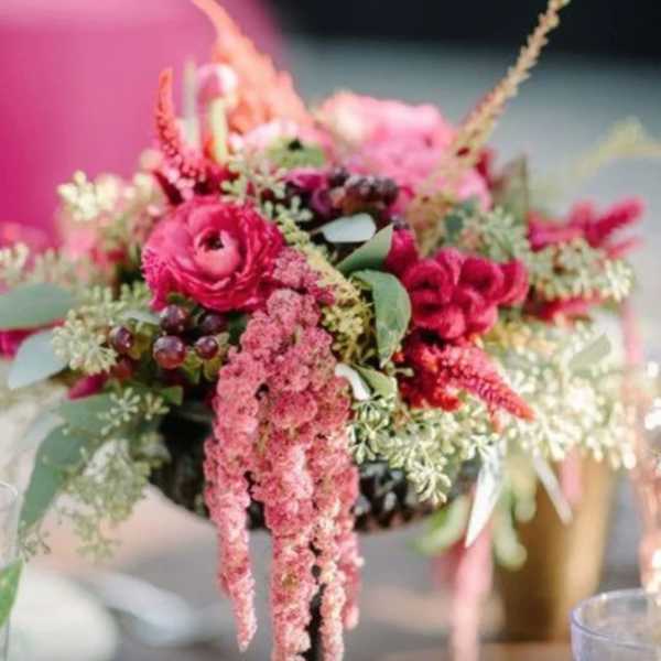 Low compote arrangement of pink and red flowers with trailing blooms and textured filler