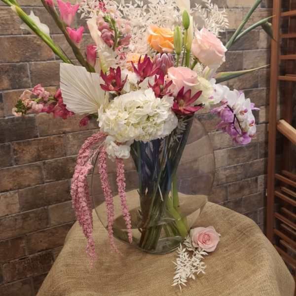 Tall mixed bouquet with pink, white, and orange flowers in a clear vase