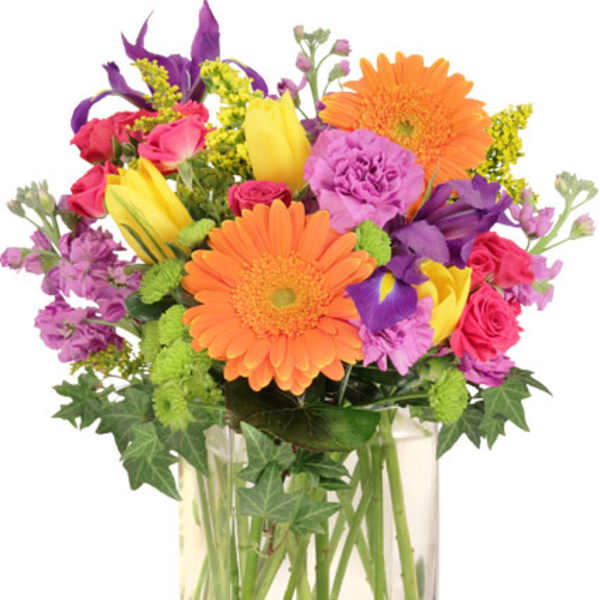 Colorful mixed bouquet in a clear glass vase with gerbera daisies and roses