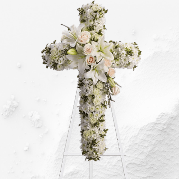 White floral cross on a stand with lilies and roses