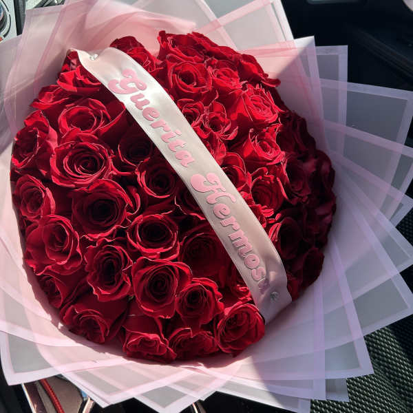 Bouquet of red roses wrapped in pink paper with a satin ribbon