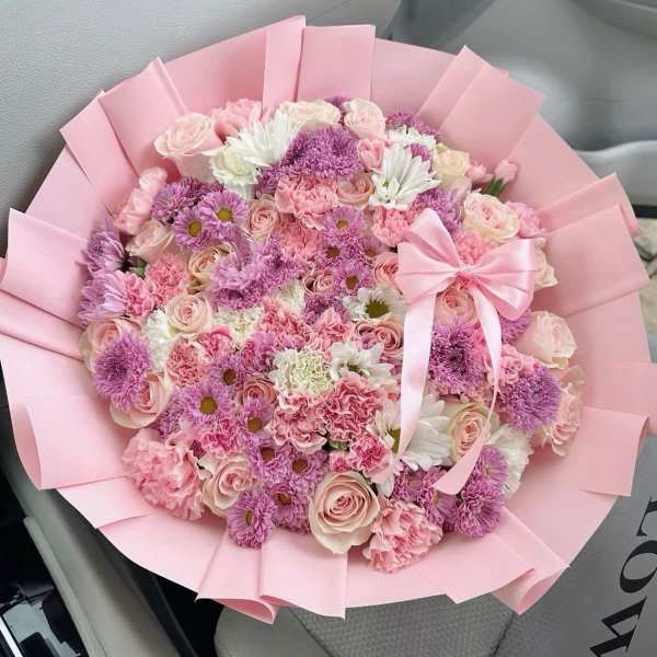 Pink and lavender bouquet with roses, daisies, and carnations wrapped in pink paper
