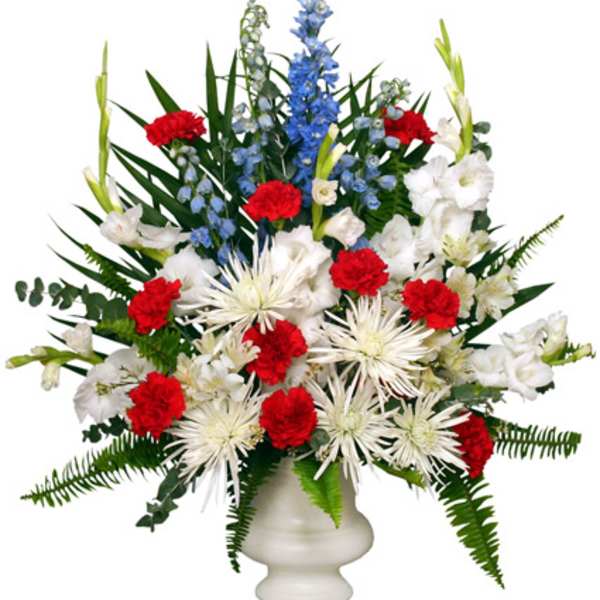 Red and white flowers in a white vase with tall blue spikes