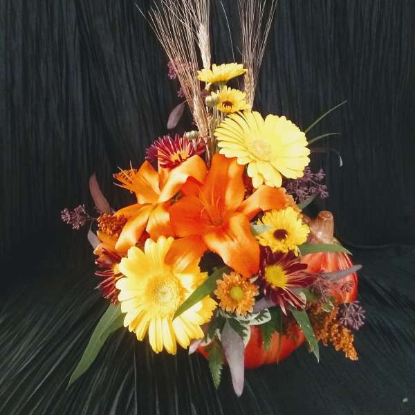 Orange and yellow floral arrangement in a pumpkin container