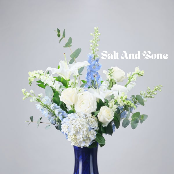 White and blue floral arrangement in a cobalt vase