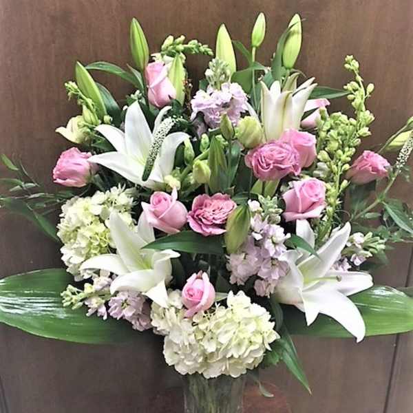 Pink roses and white lilies arranged in a clear glass vase