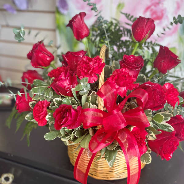 Red roses and carnations in a wicker basket with a red ribbon