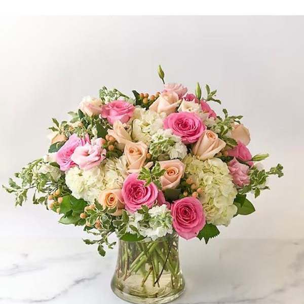 Pink and peach roses with white hydrangeas in a glass vase