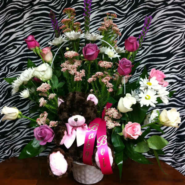 Bouquet of pink and white flowers with a teddy bear in a white basket