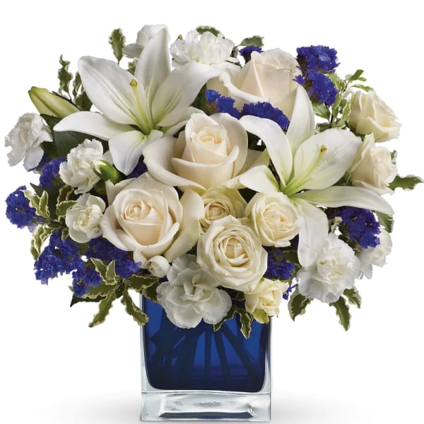 White roses and lilies arranged in a blue glass vase