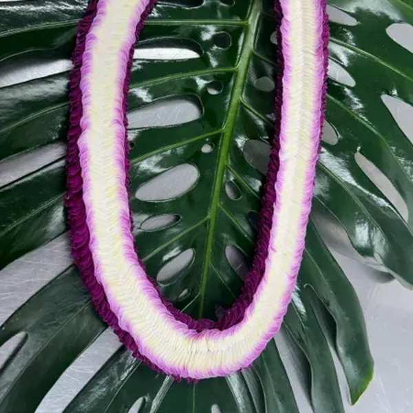Purple-and-white floral lei on large tropical leaves